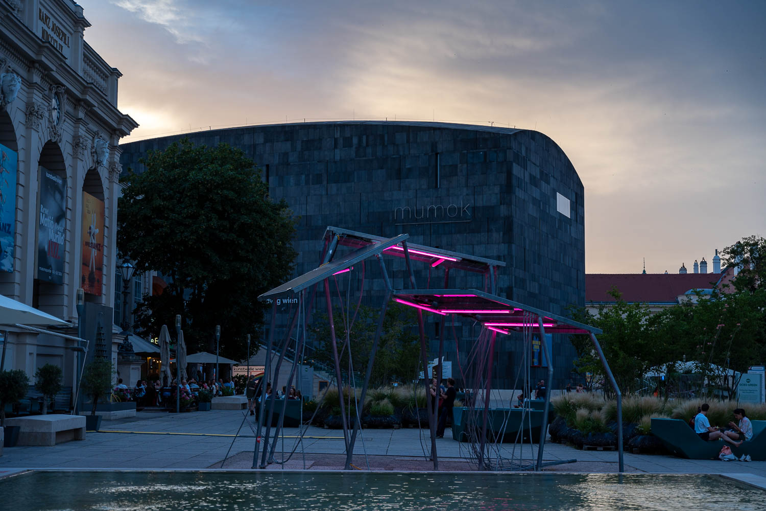 Bild vom Museumsviertel. Eine Lichtinstallation im Vordergrund. Ein Museumsgebäude weiter hinten.