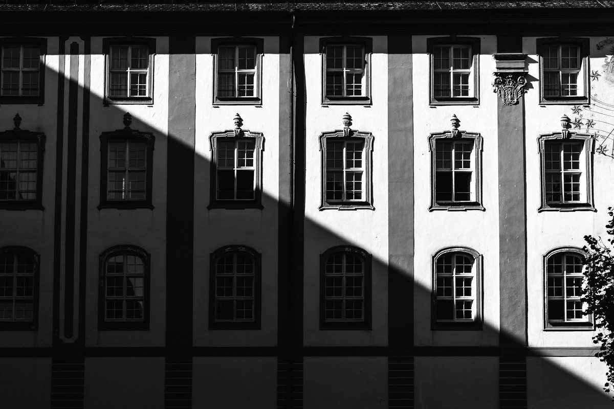 Schwarz/Weiß Außenansicht eines Hauses mit diagonal verlaufendem Schatten.
