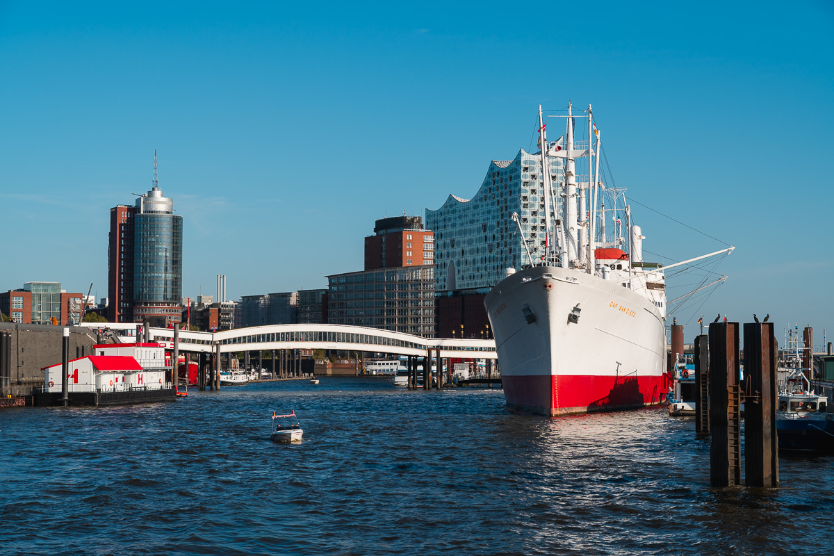 Ein (alter) Frachter liegt im Hamburger Hafen, dahiniter die Elphi.