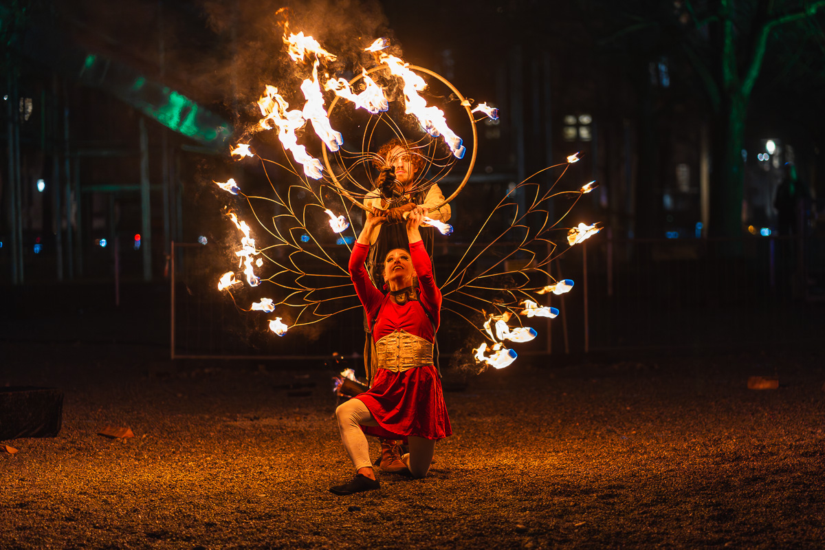 Zwei Tänzer einer Feuershow mit brennenden Accessories in Pose.